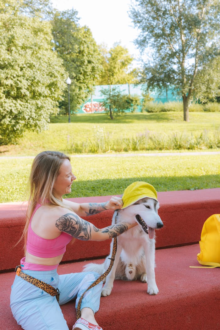 A woman in a pink tank top plays with a Siberian husky on a red bench in a sunny park.
